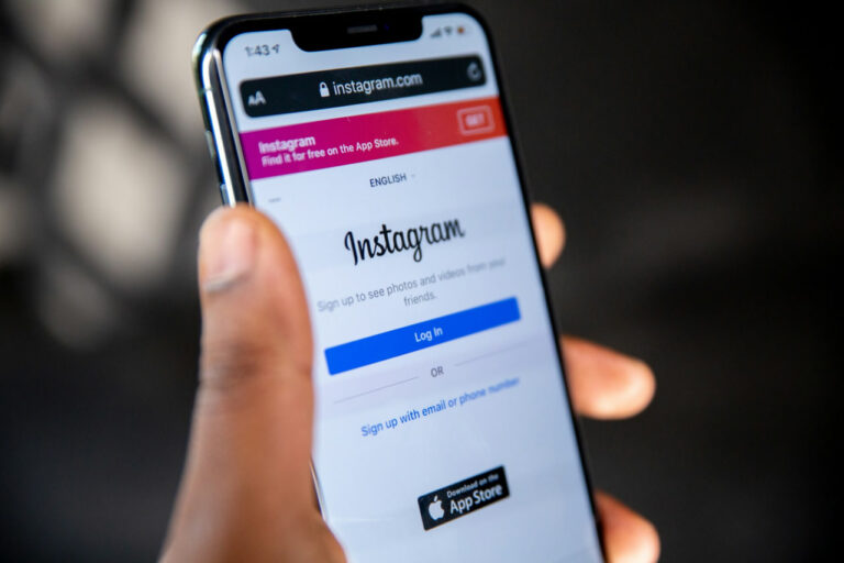 A hand holding a phone that shows a loged out instagram account